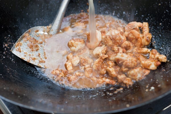 adding the chicken stock to the wok