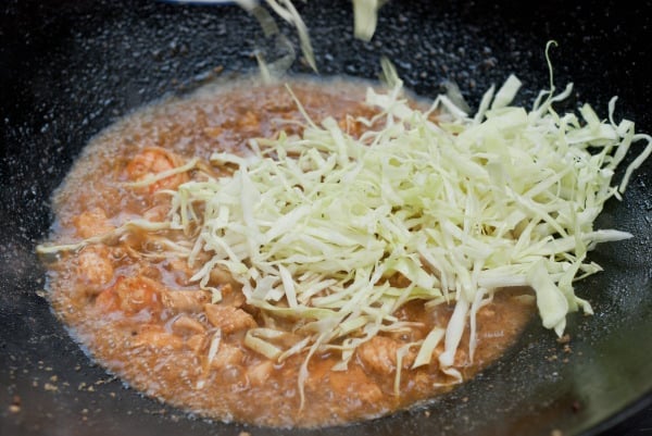 Shredded cabbage is added to the spicy chicken and shrimp mixture