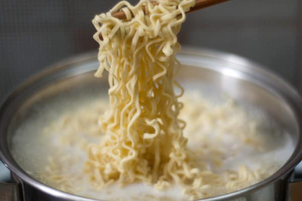 lifting curly noodles from boiling water