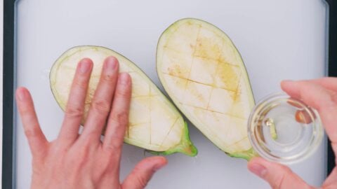 Rubbing eggplant halves with oil.