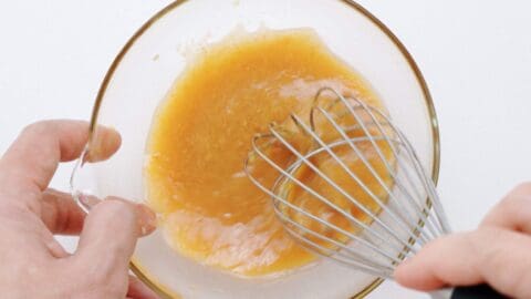 Whisking miso dressing together in a bowl.