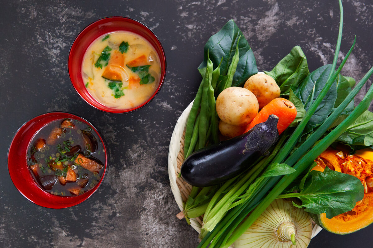 White Miso Soup and Red Miso Soup with a basket of vegetables.