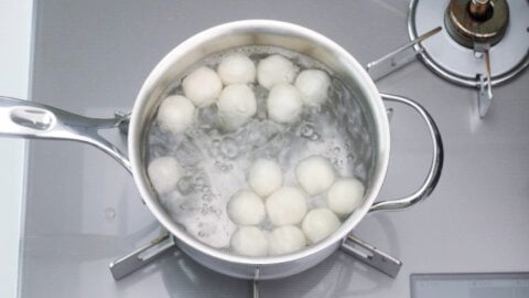 Dango floating in a pot of boiling water.