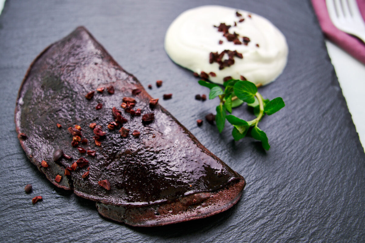 Easy stovetop chocolate omelette cake with a molten dark chocolate center, topped with cacao nibs and whipped cream.