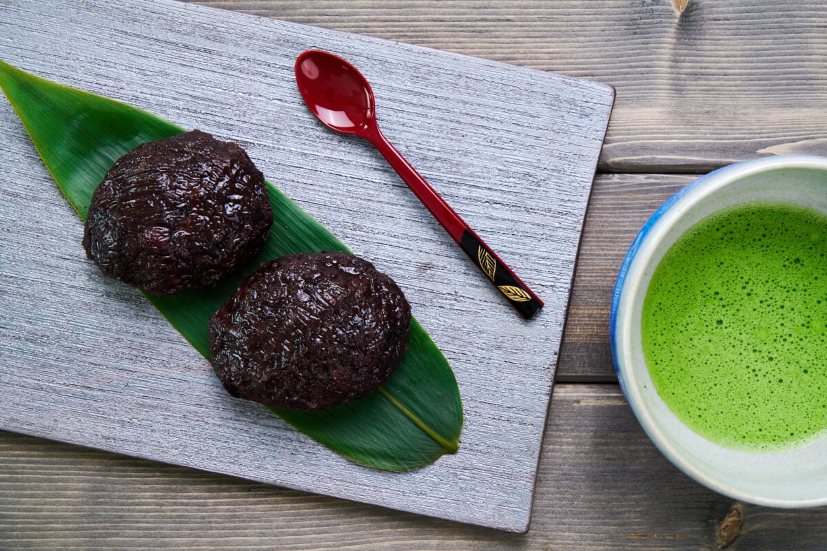 Botamochi or Ohagi on a bamboo leaf with a bowl of matcha tea.