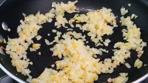 Browning onions and garlic in a frying pan for taco rice.