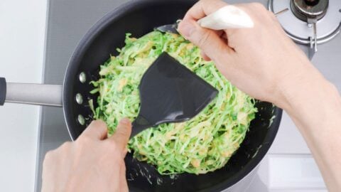 Shaping okonomiyaki in a frying pan.