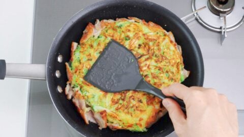 Shaping Okonomiyaki with a spatula.