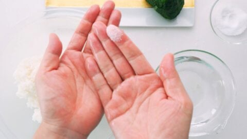 Wet hands with salt for making onigiri rice balls.