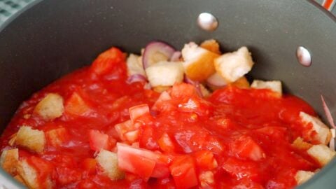 Adding tomatoes to sautéed bread.