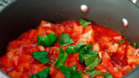 Adding fresh basil leaves to bread and tomato soup.