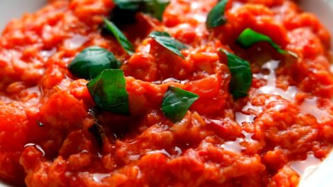 Pappa al Pomodoro garnished with a drizzle of olive oil and torn basil leaves.