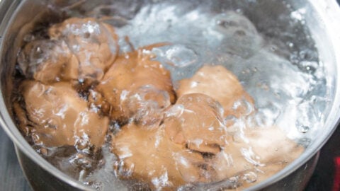 Brown eggs in a large pot at a rolling boil.