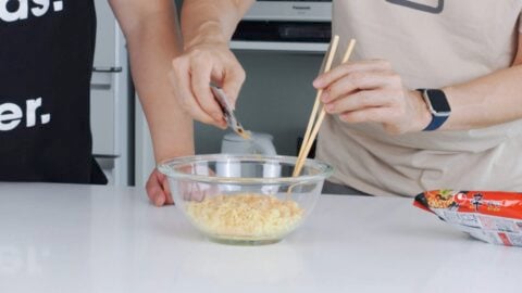 Mixing seasoning packet into cooked ramen noodles.