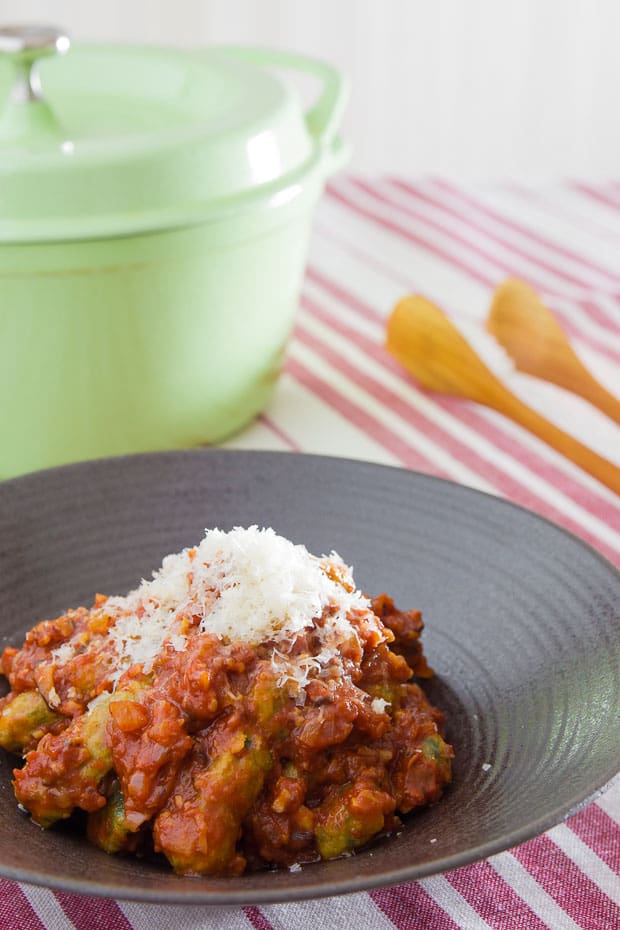 Malfatti enrobed in sugo and crowned with Parmesan cheese.