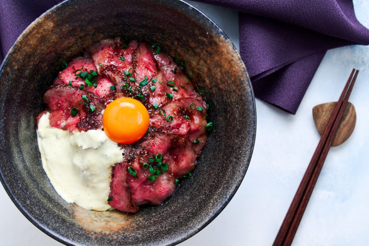 Japanese roast beef donburi topped with wasabi cream and an egg yolk.