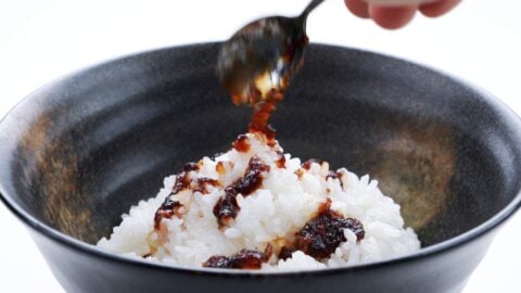 Drizzling onion sauce onto a bowl of rice.