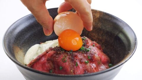 Topping roast beef bowl with an egg yolk.