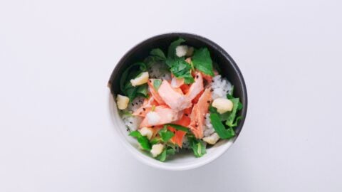 Rice topped with salted salmon, sesame seeds, rice crackers and herbs.