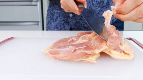 Trimming excess fat and connective tissue from chicken thighs.