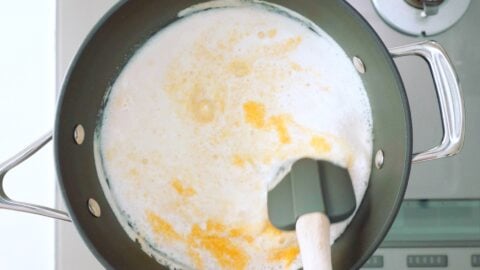 Stirring grits into a pot of milk and chicken stock.