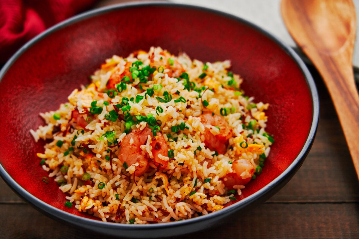 Best shrimp fried rice in a red bowl on a dark wooden table.