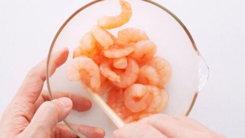 Marinating small pink shrimp in a glass bowl.