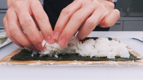 Spreading out vinegared sushi rice on nori.