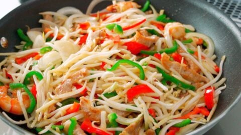 Onions, bell peppers, beansprouts and bamboo shoots being stir-fried for Singapore Rice Noodles.