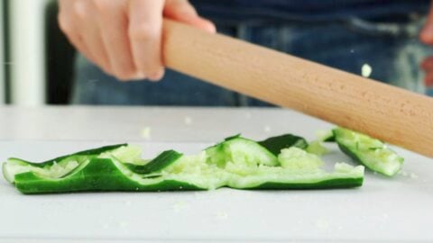 Smashing a cucumber with a rolling pin.