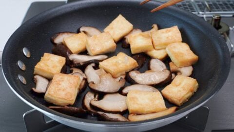 Shiitake mushrooms and tofu in a frying pan.