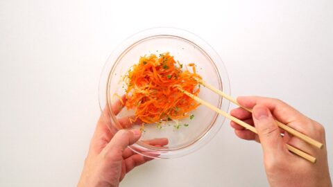 Mixing carrot salad with chopsticks.