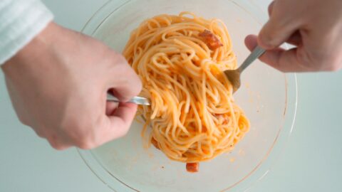 Tossing Spaghetti alla Carbonara together in a bowl.