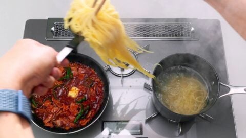 Transferring boiled spaghetti to a pan with the sauce for making Japanese Napolitan.