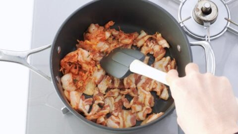 Browning pork belly and kimchi in a pan.