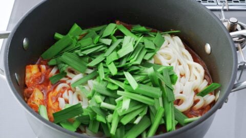 Garlic chives and udon noodles added to kimchi soup.