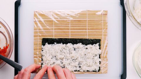 Sushi rice on nori for making spicy tuna hosomaki.