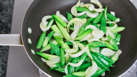 Spring onions, snap peas, and asparagus in a frying pan, for spring pasta.