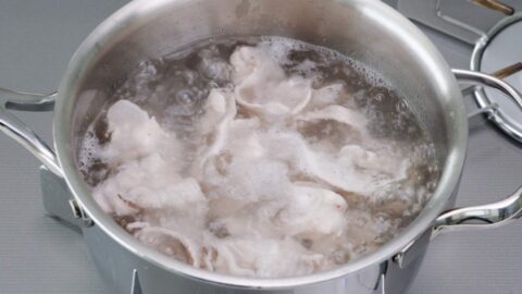 Pork belly slices in boiling water.