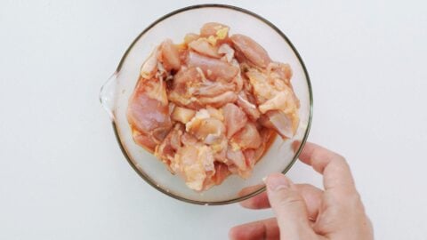 Marinating chicken with ginger, soy sauce, and sake for sweet and sour chicken.