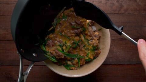 Sliding beef and egg onto the donburi of rice.