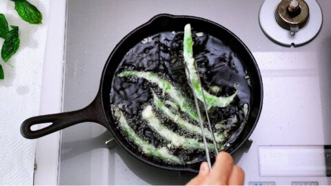 Frying tempura green beans in a cast iron pan.