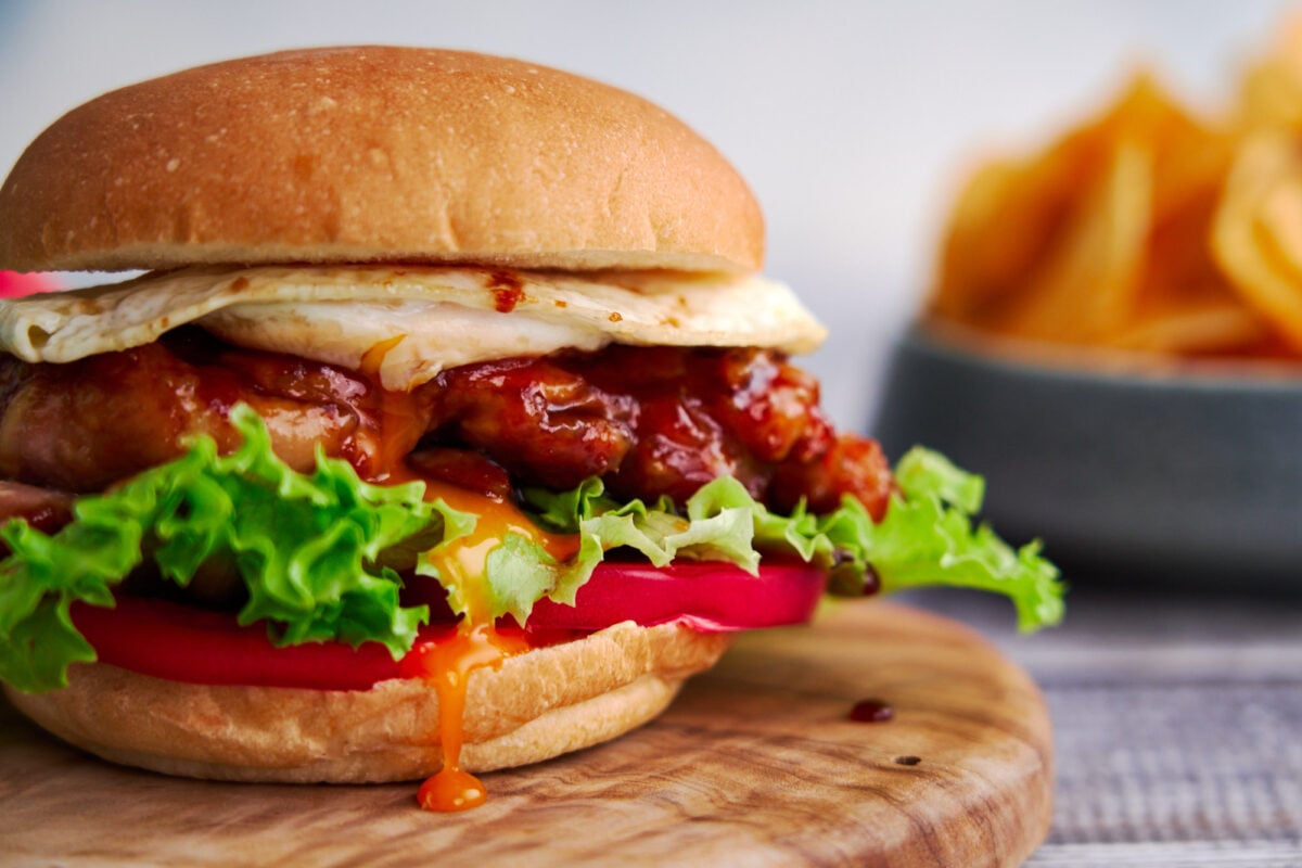 Teriyaki chicken and molten fried egg sandwich with lettuce and tomatoes.