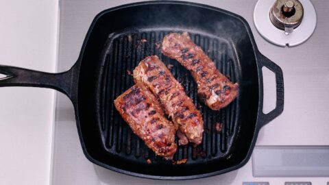 Overhead shot of hanger steaks on grill pan with grill marks.