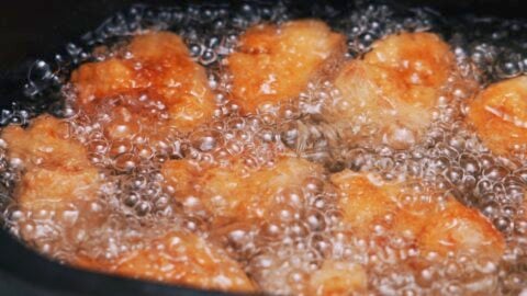 Karaage tofu deep frying in a black pot.