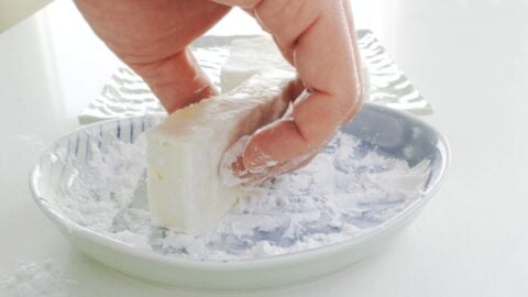 Dusting tofu with potato starch.