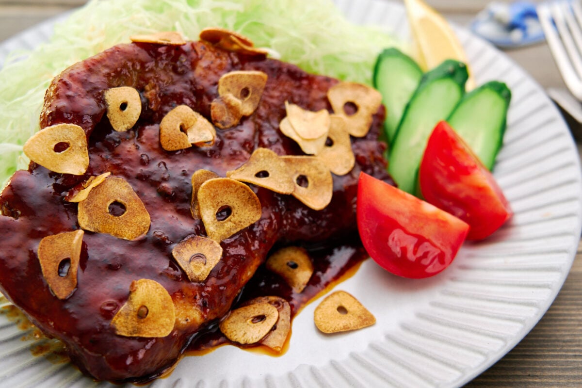 This tender, juicy Japanese pork steak, or Tonteki, is glazed in a savory sweet sauce and topped with crispy fried garlic.