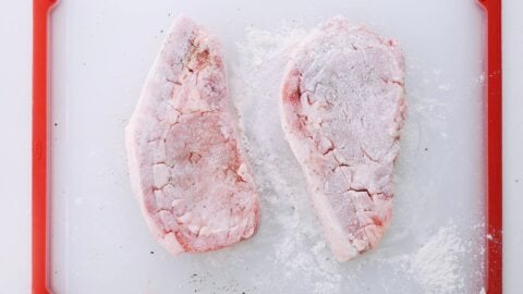 Pork steaks seasoned with salt and pepper and dusted with flour.