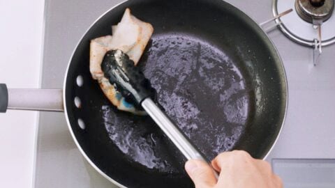 Wiping out the excess oil from the pan.