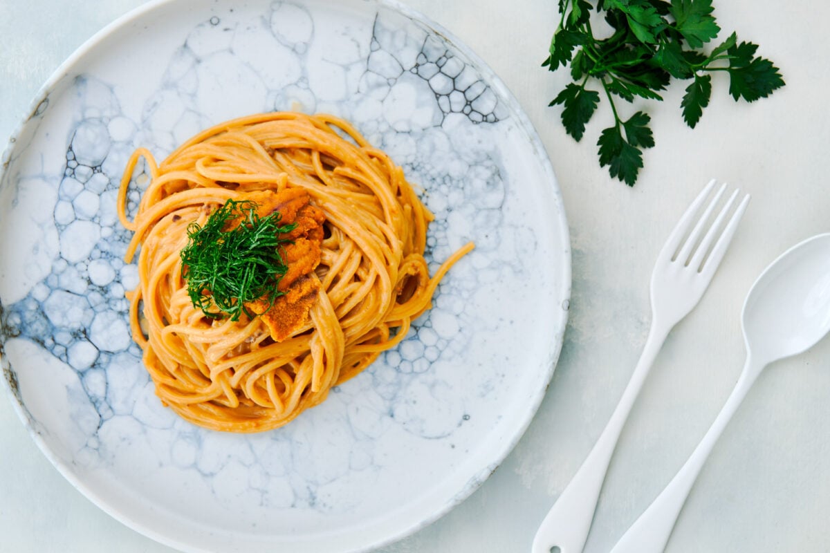 Tangle of Uni spaghetti with a creamy sea urchin sauce, garnished with fresh uni and green shiso.